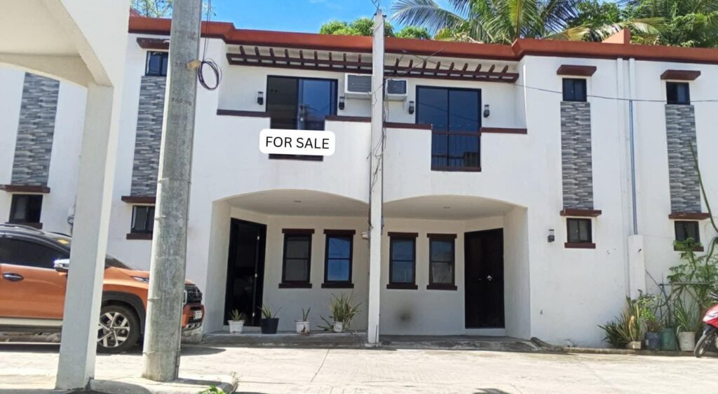 Exterior shot showing the entrance, balcony, and a vehicle parked in the private carport area.