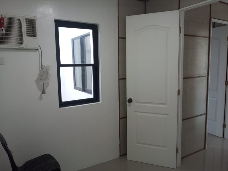 Interior of a bedroom showing the pre-installed window AC unit and large sliding glass doors leading to the balcony.